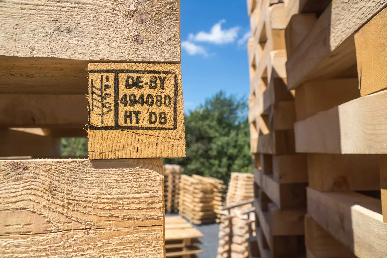 Gestapelte Holzverpackungen, im Vordergrund ein Kantholz mit eingebranntem IPPC-Stempel DE-BY 494080 HT